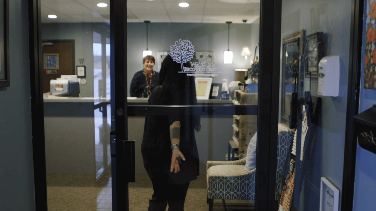 A client enters the doors of Wayside Recovery Center and is greeted by Stephanie at the front desk.