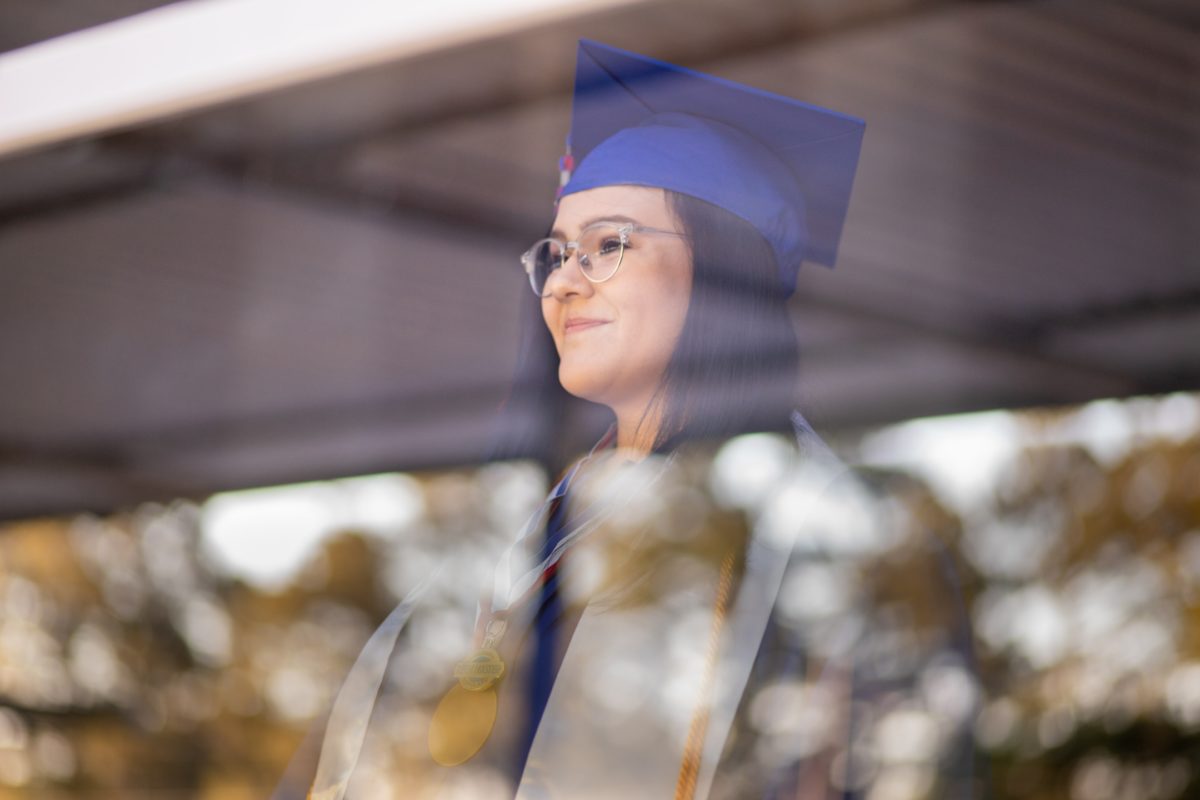 A woman in a graduation cap smiling and looking out a window
